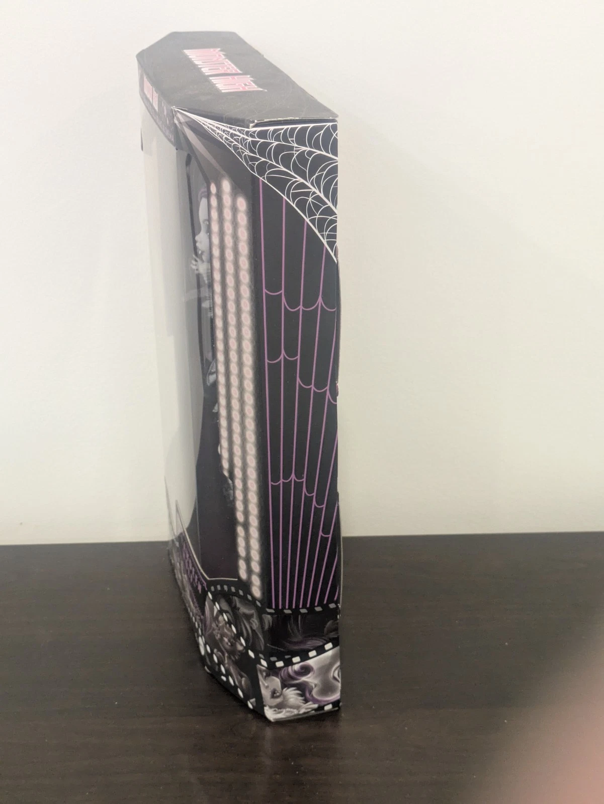 Vista lateral de la caja de Monster High Reel Drama Clawdeen Wolf con diseño de telarañas.